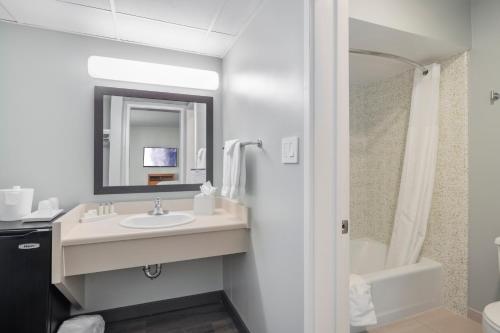 a bathroom with a sink and a mirror and a tub at Vagabond Inn Glendale in Glendale