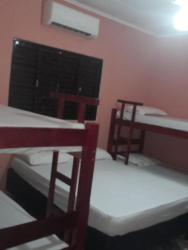 a room with three bunk beds and a table and a window at Casa Richarti in Olímpia