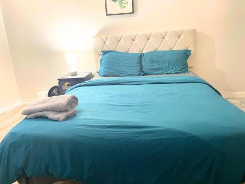 a bed with blue sheets and blue pillows at Flowealth Suites - Private Rooms Near West Edmonton Mall in Edmonton