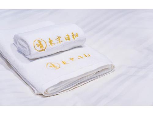 Una toalla blanca con escritura dorada sobre una cama. en Tokyo Biyori Hotel - Vacation STAY 07393v, en Tokio