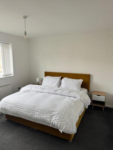 Lemingtonにある2 bedroom flat in Newcastle - Free street parkingの白いシーツと枕が付いた大きなベッドのある寝室