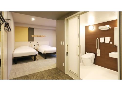 a bathroom with two beds and a toilet in a room at Smile Hotel Kanazawa Nishiguchi Ekimae - Vacation STAY 11502v in Kanazawa