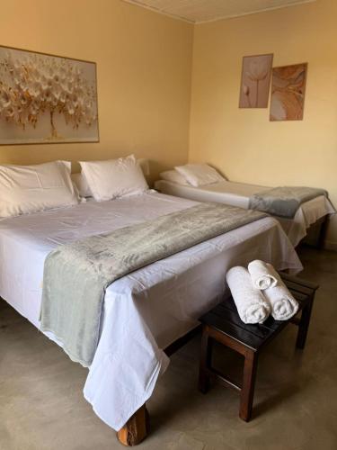 two beds in a room with towels on a table at Pousada/Camping Mirante Serrano in Alto Paraíso de Goiás