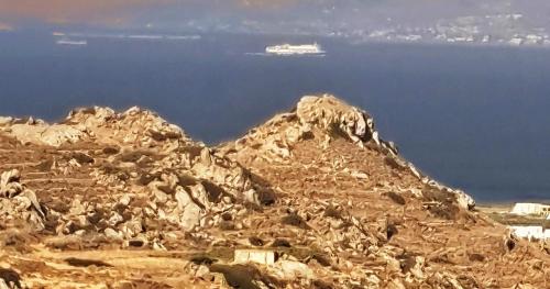 a rocky mountain with a cruise ship in the background at YouGa Nest in Vívlos