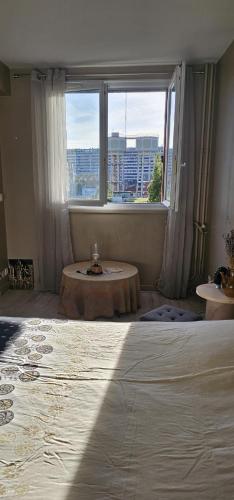 a bedroom with a large window and a coffee table at Le calme ensoleillé in Paris