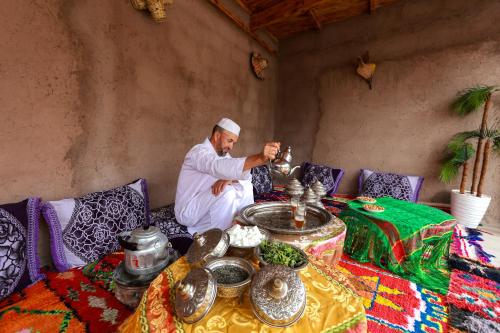 a man sitting on a couch with a table with food at Dar Tamatert in Tamatert