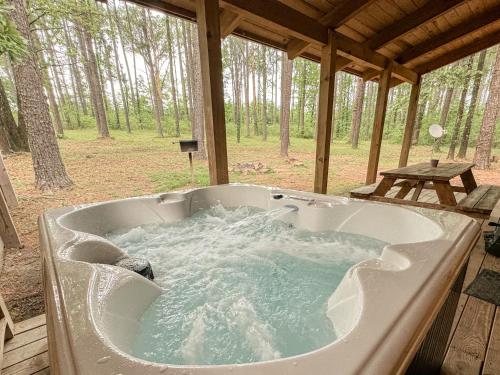 a jacuzzi tub sitting on a deck with a picnic table at Ozark Cabin 9 miles to DeGray Lake Private Hot Tub Fishing on Site in Bismarck