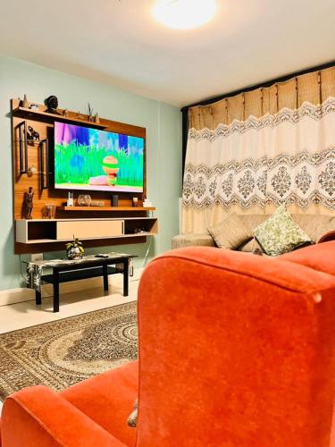 a living room with an orange couch and a flat screen tv at MORRO do MOCO in Windhoek