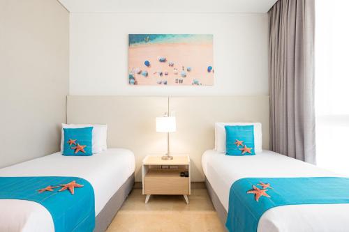 two beds in a room with blue and white at Grand Marina Suites Santa Marta in Santa Marta