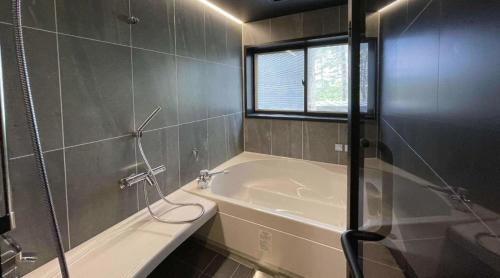 a bathroom with a tub and a shower with a window at TOCORO. Mt.Fuji CAMP & GLAMPING - Vacation STAY 23388v in Oishi