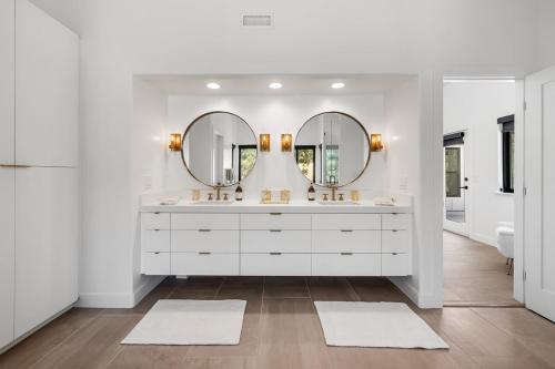 ein weißes Badezimmer mit zwei Waschbecken und Spiegeln in der Unterkunft Sunset View Luxury Living on 5 Picturesque Acres in Atascadero