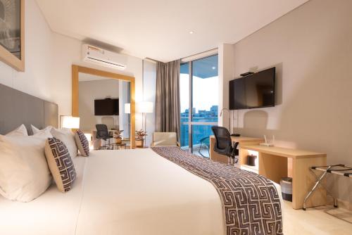 a hotel room with a large bed and a large window at Grand Marina Suites Santa Marta in Santa Marta