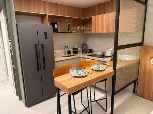 a kitchen with a wooden table and a refrigerator at Apartamentos Exclusivos no Edifício City House in Barreiras