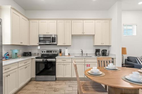a kitchen with white cabinets and a wooden table at The Flamingo Nest - Kid Friendly in Orlando