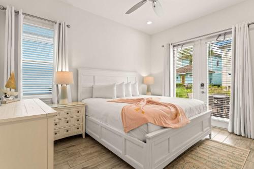 a white bedroom with a bed and a desk and windows at The Flamingo Nest - Kid Friendly in Orlando