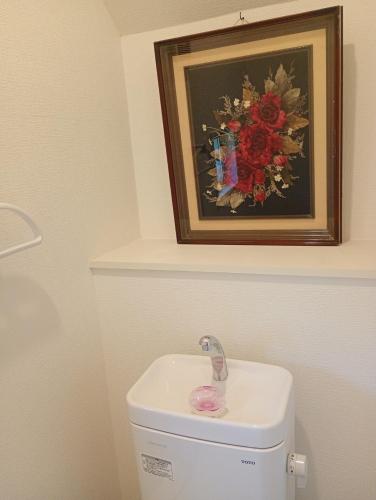a picture of a flower painting above a toilet at ShirokumaHouse - Vacation STAY 24594v in Wakayama
