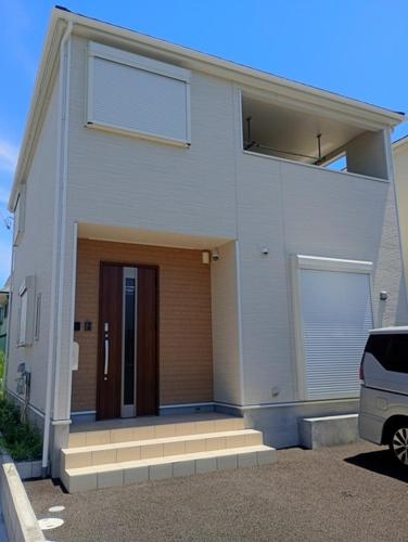a white house with a door in a parking lot at ShirokumaHouse - Vacation STAY 24594v in Wakayama