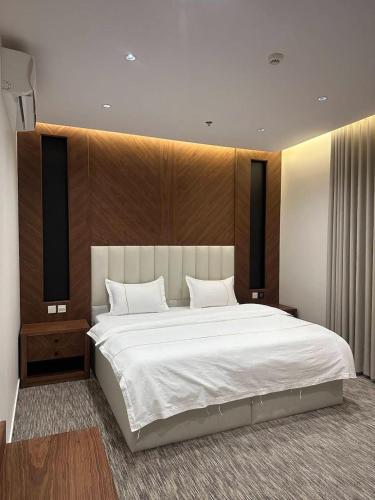 a bedroom with a large bed with a wooden headboard at شقق جولدن إن للشقق المخدومة بجوار مستشفي السعود الالماني in Khamis Mushayt