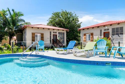 a pool with blue and green chairs and a house at Residences at Barrier Reef Casita 3 by Stay Floreo in San Pedro Island
