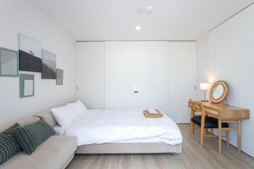 a white bedroom with a bed and a desk at CAN LI ASSO - Vacation STAY 25393v in Minami Aso