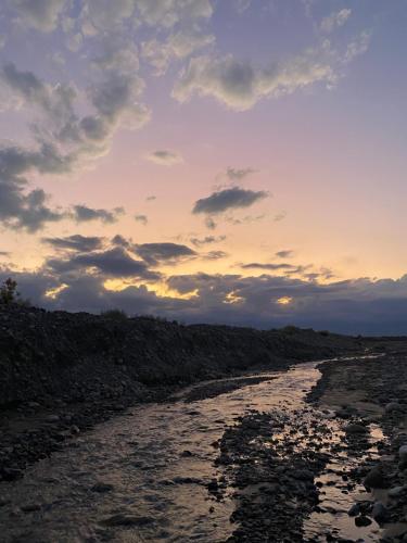a sunset over a rocky shoreline with a river at Finca La Pichona in Los Árboles