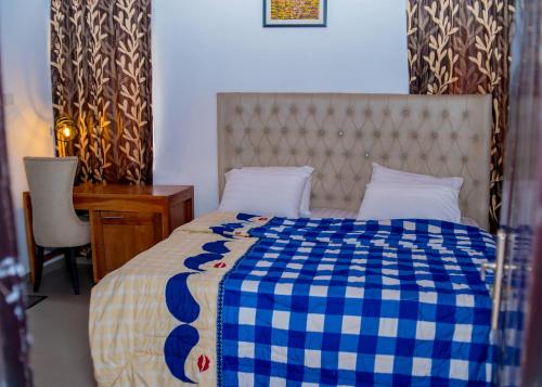 a bedroom with a bed with a blue and white checkered blanket at Creekwood Apartment Oshogbo in Oshogbo