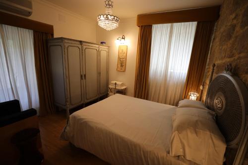 a bedroom with a bed and a cabinet and windows at Casa dos Macieis - Entire Main House, Entire Guesthouse or Separate Wing of Main House - Camino Santiago direct access & Optional Agritourism in Facha