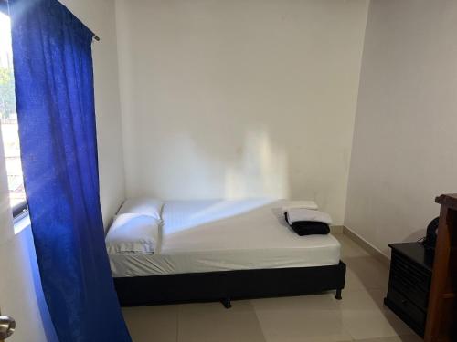 a small bedroom with a bed with a blue curtain at Apartamento cómodo con excelente ubicación in Medellín