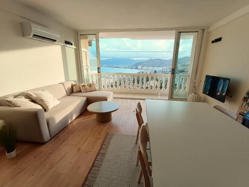a living room with a couch and a large window at LOFT ROYAL - apartamento "loft" con terraza y vistas al mar in Faro de Cullera