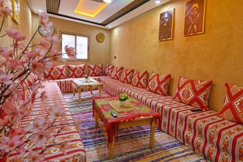 a waiting room with red couches and a table at Dar Tamatert in Tamatert