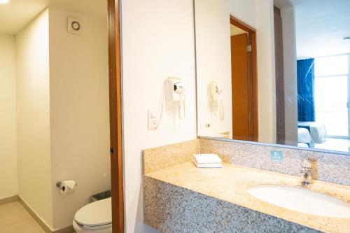 a bathroom with a sink and a toilet and a mirror at Oceano Palace in Mazatlán