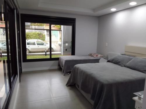 a bedroom with two beds and a large window at StudioD in Passo Fundo