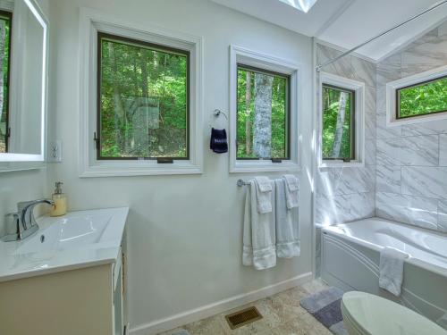 a white bathroom with a tub and a sink at Windows Over Waterfalls in Hot Springs