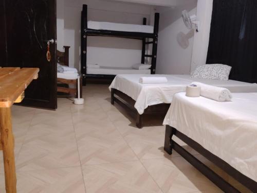 a bedroom with two beds with white sheets and a desk at Hotel Hacienda Sanabria in Tauramena