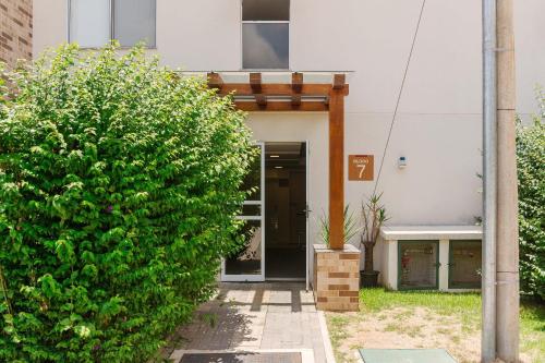 a building with a large green bush in front of it at Apto. moderno em condomínio com piscina CME0107 in Itaipava