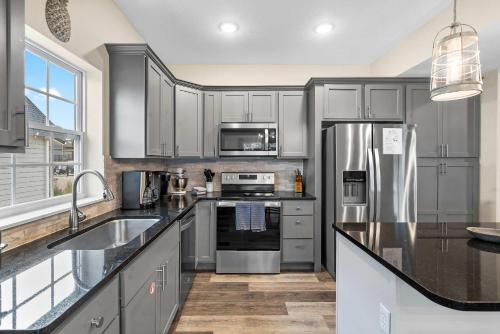 a kitchen with gray cabinets and a stainless steel refrigerator at Pineapple Bungalow - 14ppl in Hollister