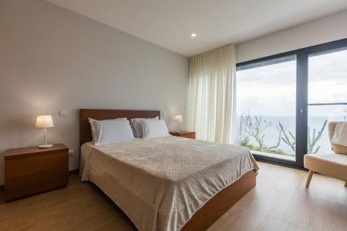 a bedroom with a bed and a large window at Fonte Da Rocha - OCEAN VIEW in Ponta Delgada