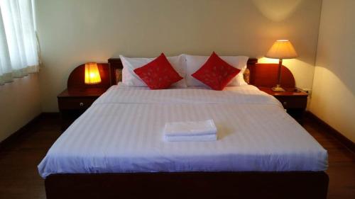 a bedroom with a large white bed with red pillows at Poonchock Mansion in Bangkok