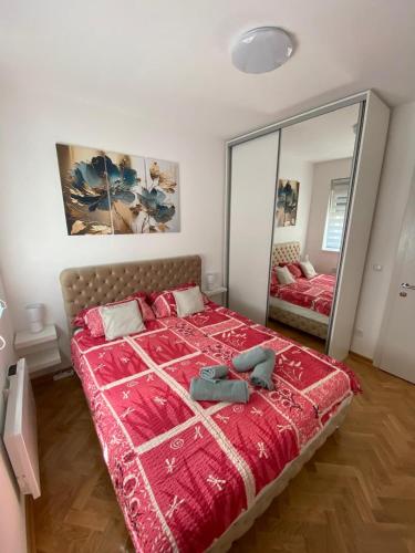 a bedroom with a red bed with a large mirror at Apartman Sunny, Vrnjacka Banja in Vrnjačka Banja