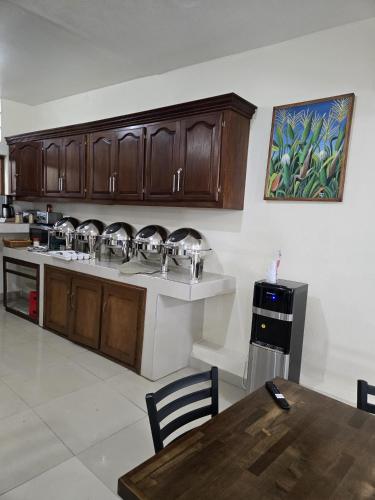 a kitchen with wooden cabinets and a sink and a table at Comfort Plus Hotel in Cap-Haïtien