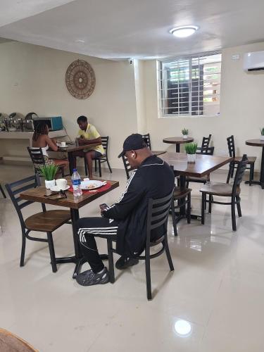 a man sitting at a table in a restaurant at Comfort Plus Hotel in Cap-Haïtien