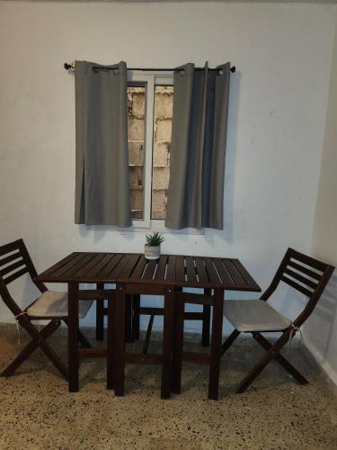 a wooden table with two chairs and a window at First Floor Apartment in La Ceiba