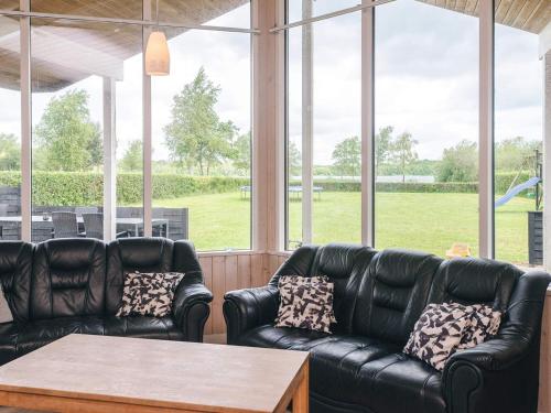 a screened in porch with two leather couches and a table at 10 person holiday home in Ansager-By Traum in Ansager