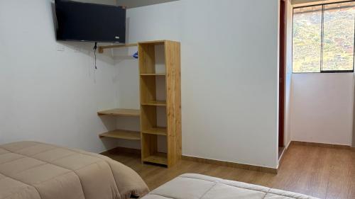 a room with a bed and a tv on a wall at Apus Guest House in Huaraz