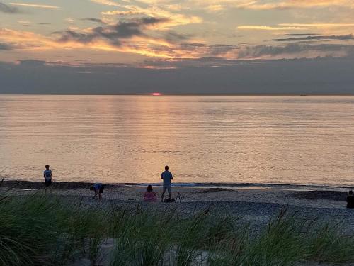 a group of people standing on the beach at sunset at 2 person holiday home in Skagen-By Traum in Skagen