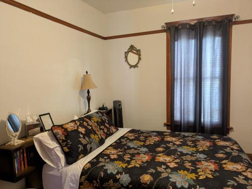 a bedroom with a bed with a flowered blanket and a window at The Oliver House - Adults Only in Bisbee