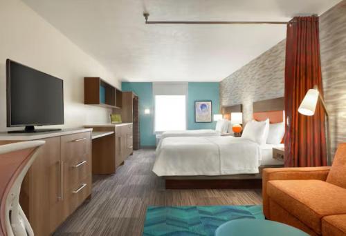 a hotel room with a bed and a flat screen tv at Home2 Suites By Hilton Hayward in Hayward
