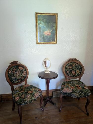 two chairs and a table with a mirror and a painting at The Oliver House - Adults Only in Bisbee
