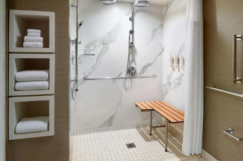a bathroom with a shower with a bench in it at Charlotte Marriott SouthPark in Charlotte
