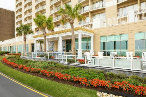 an exterior view of a building with palm trees and flowers at SpringHill Suites by Marriott Virginia Beach Oceanfront in Virginia Beach